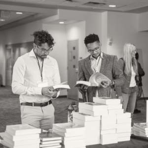 Two people standing and flipping through textbooks
