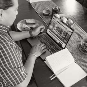 Man working on a laptop with a sandwich and notebook on the table