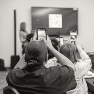 View from back of room with people recording with their phones