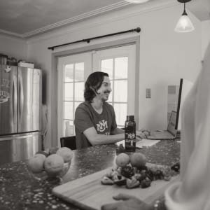 Individual smiling and working on a laptop with open red UNM water bottle beside them